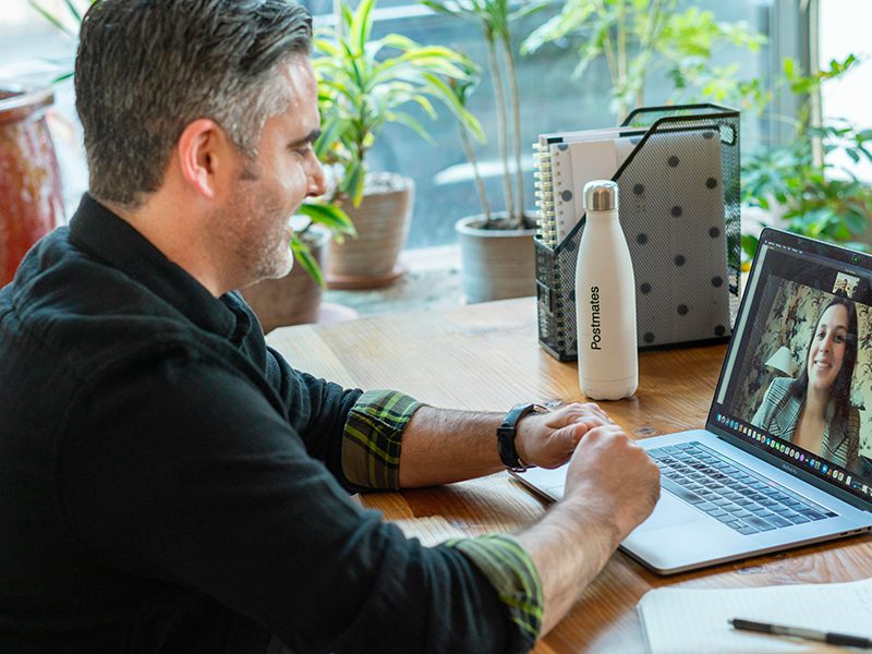 A man on a laptop at his desk engaged in a zoom meeting with a woman smiling.