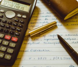 A calculator and a legal pad with calculations on it;