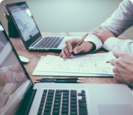 Two laptop keypads and a shared notepad between them with two researchers collaborating