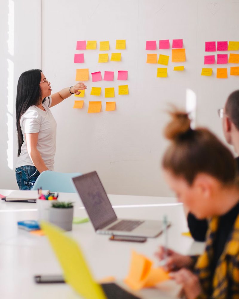 Woman leading a meeting with colorful notes on the wall.